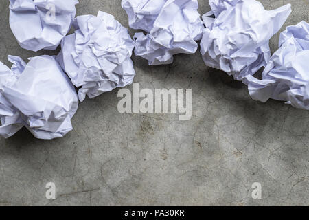 Boules de papier froissé sur une surface de béton gris Banque D'Images