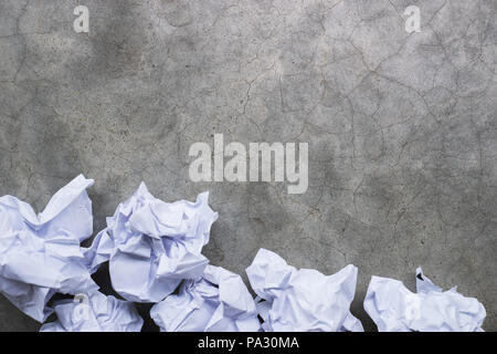 Boules de papier froissé sur une surface de béton gris Banque D'Images