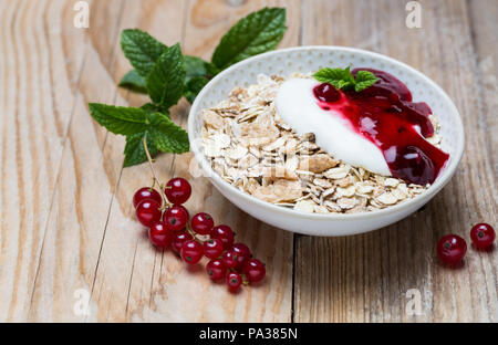 Gelée de fruits rouges muesli avec du yaourt et le gruau sur fond de bois. Banque D'Images