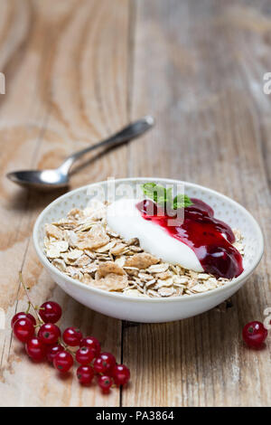 Gelée de fruits rouges muesli avec du yaourt et le gruau sur fond de bois. Banque D'Images