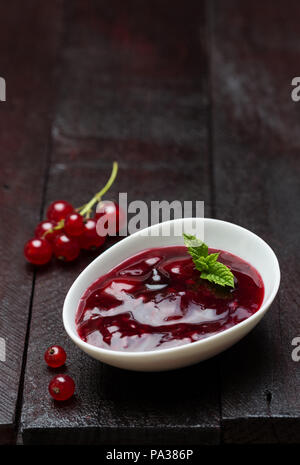 Gelée de fruits rouges avec les raisins dans un plat sur une surface en bois. Banque D'Images