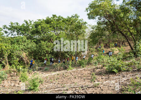 Un groupe de personnes habillées de couleurs vives d'un côté la montagne randonnée à travers une forêt. Banque D'Images