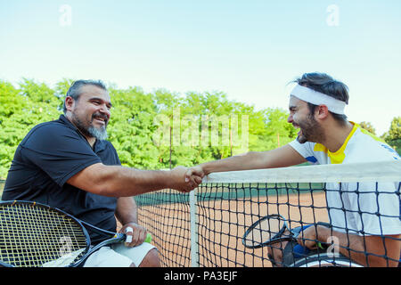 Paire de mobilité les joueurs de tennis se serrer la main dans le filet après le tournoi de plein air Banque D'Images