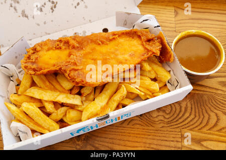 Poisson-frites servi avec sauce au cari à Tynemouth en Angleterre. Le plat est repas britannique traditionnel. Banque D'Images