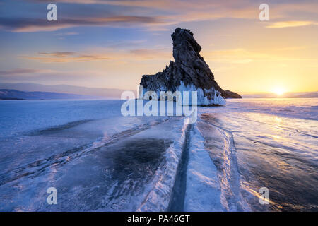 Le lac Baïkal en été lever du soleil en hiver. Belles pierres et lignes de fissures dans la glace. Banque D'Images