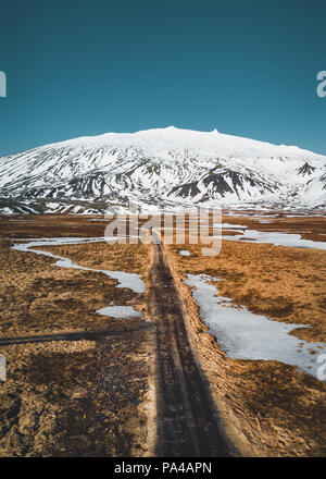 Photo d'un drone aérien vide quitter road route vers une énorme montagne volcanique Snaefellsjokull au loin, près de Snaefellsjokull parc national, de l'Islande. Banque D'Images