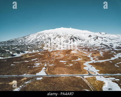 Photo d'un drone aérien vide quitter road route vers une énorme montagne volcanique Snaefellsjokull au loin, près de Snaefellsjokull parc national, de l'Islande. Banque D'Images