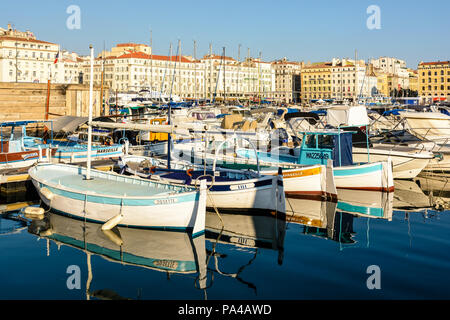 Le Vieux Port de Marseille, France, avec de vieux bateaux de pêche amarrés dans l'eau morte et les bâtiments du Quai des Belges baigné de lumière chaude. Banque D'Images