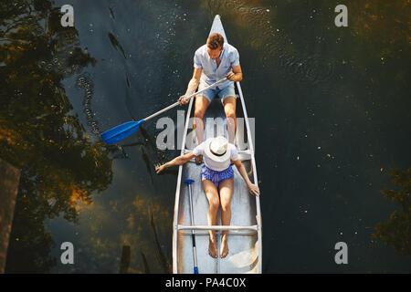 High angle d'un jeune couple assis dans un canoë kayak ensemble sur un lac encore en été Banque D'Images