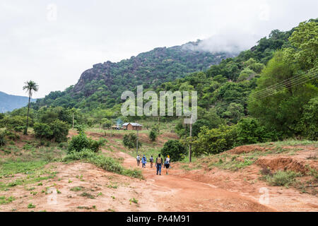 Un groupe de personnes habillées de couleurs vives randonnées à flanc de montagne. Banque D'Images