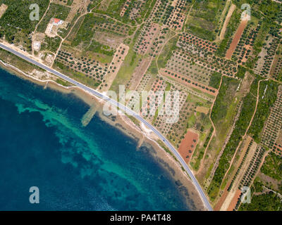 Vue aérienne d'une route qui longe la côte croate et passe à travers des champs agricoles, avec les plantations et les champs cultivés. Littoral Banque D'Images