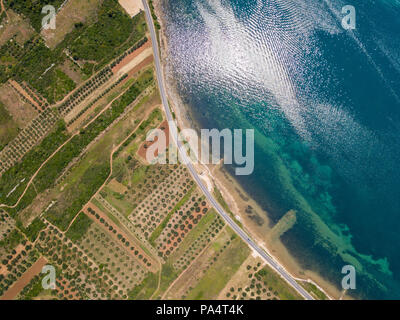 Vue aérienne d'une route qui longe la côte croate et passe à travers des champs agricoles, avec les plantations et les champs cultivés. Littoral Banque D'Images