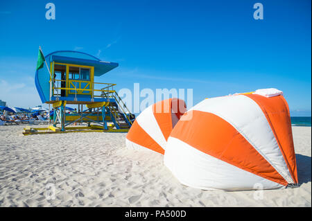 Vue panoramique de l'emblématique tour sauveteur jaune et bleu et parasols sur South Beach, Miami Banque D'Images