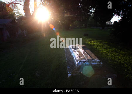 Sunbeam illuminant une tombe dans un cimetière de l'église paroissiale. Banque D'Images