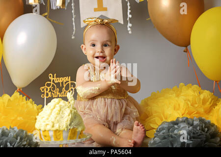 Beau bébé mignon assis sur un fond gris de guirlandes et de drapeaux avec des ballons. La célébration de la première année de vie Banque D'Images