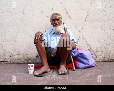 ANTIPOLO CITY, PHILIPPINES - le 6 novembre 2015 : Un vieux mendiant est assis à un trottoir à solliciter des fonds auprès des passants. Banque D'Images