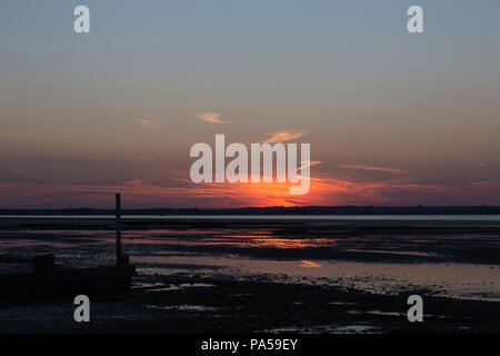 Éclats de lumière vive des nuages au coucher du soleil de Seasalter, Whitstable, Kent, UK. Un brise-lames ou épi est visible au premier plan. Banque D'Images