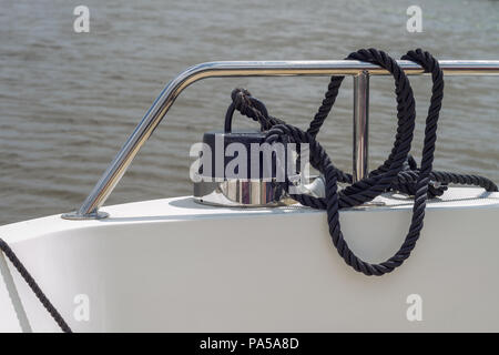 Une corde noir attaché à un poids sur un bateau attaché à la rambarde métallique Banque D'Images