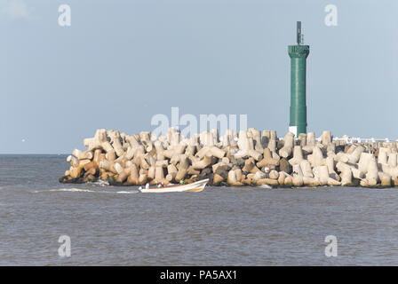 COATZACOALCOS, VER/MEXIQUE - Juillet 18, 2018 : un bateau de pêche à l'embouchure de la rivière Coatzacoalcos. Les tétrapodes de béton sur le brise-lames et d'un phare Banque D'Images