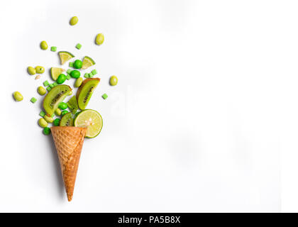 Ice cream cone télévision lay image avec bonbons vert kiwi et son emballage dans le cône. Banque D'Images