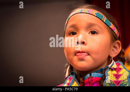 Close up portrait of Little Native American girl habillé en bandeau coloré, d'oreille et à la robe de l'avant avec la langue entre les lèvres. Banque D'Images