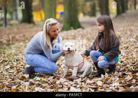 Mère et fille avec leur labrador retriever chiot du parc. Banque D'Images