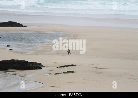 Silhouette d'un homme marchant dans l'immense plage de Newquay, une destination populaire pour les surfeurs. Newquay, Cornwall, UK Banque D'Images