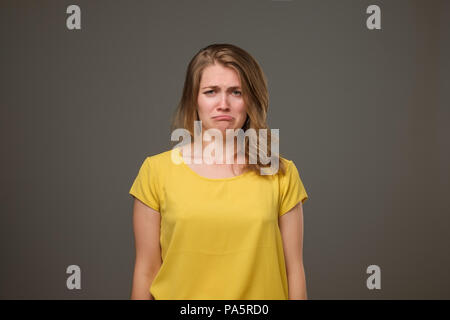 Portrait de femme européenne mécontentement face au mécontentement, fronce chercher désespérément à l'appareil photo, aller à pleurer debout sur fond noir. Banque D'Images