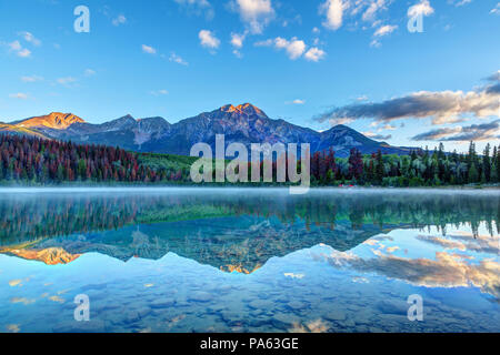 Lever de soleil sur lac Patricia dans le Parc National Jasper avec Pyramid Mountain en arrière-plan et brumeux brouillard sur la surface de l'eau. Eaux calmes se créer Banque D'Images