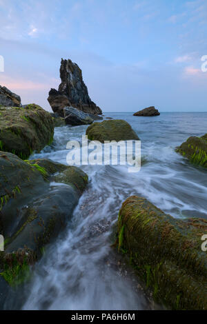 La première lumière sur Little Downderry Beach dans le sud-est avec vue sur le rocher de Cornwall Longstone Banque D'Images