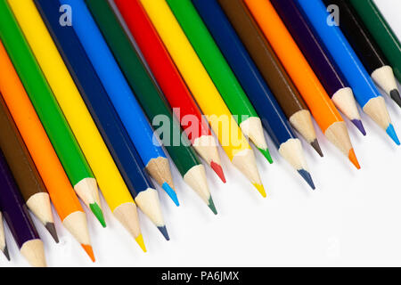 Crayons de couleur alignés dans une rangée sur un fond blanc. Banque D'Images