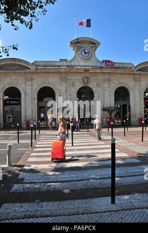 Jeune étudiant français avec valise rouge à dos après son arrivée à la gare de Béziers Banque D'Images