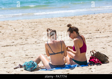 Bournemouth, Dorset, UK. 21 juillet 2018. UK : météo chaude et ensoleillée à Bournemouth plages, comme chef de la mer sunseekers pour profiter du soleil au début des vacances d'été. Deux jeunes femmes en train de bronzer sur une plage. Credit : Carolyn Jenkins/Alamy Live News Banque D'Images