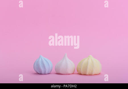 Trois meringues multicolores sur un fond rose et copyspace pour le texte Banque D'Images
