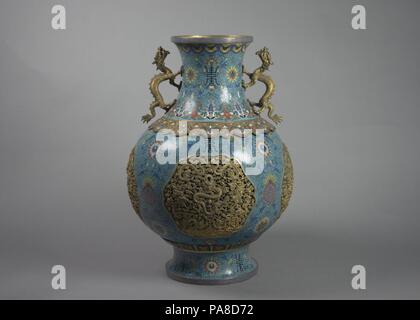 L'un d'une Paire de vases avec Dragon poignées. Culture : la Chine. Dimensions : H. 18 1/2 in. (47 cm) ; Diam. En 13. (33 cm) ; Diam. de la jante 6 1/4 in. (15,9 cm) ; Diam. de 7 3/8 in. (18,7 cm). Date : du 19e siècle. Le cloisonné est une technique de création de dessins sur des boîtiers métal où fabriqués à partir de cuivre ou de bronze sur le fil qui a été tordue ou martelée dans un motif désiré sont remplis de pâte de verre de couleur. Connu sous le nom de cloisons (Français pour 'partitions'), les boîtiers sont généralement collées ou soudées sur le corps de métal. La pâte de verre, ou l'émail, est coloré avec de l'oxyde métallique et peint dans les co Banque D'Images