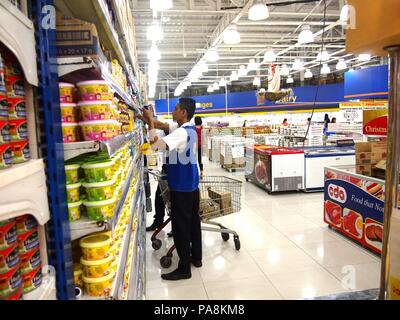 ANTIPOLO CITY, PHILIPPINES - le 19 novembre 2015 : Un employé de supermarché produits organise sur un présentoir. Banque D'Images