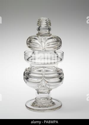 Bol de sucre. Culture : L'Américain. Dimensions : 9 7/8 x 4 3/8 in. (25,1 x 11,1 cm). Bouilloire : attribuée à New England Glass Company (Américain, East Cambridge, Massachusetts, 1818-1888) ; peut-être en verre de South Boston fonctionne. Date : 1815-35. Verre, couper finement gravés ou dans une variété de modèles basés sur les styles Régence anglaise, a été en vogue pour un art de la table au début du xixe siècle. Cet élégant sucrier et sa crème connexes pitcher révèlent une alternative sophistiquée à la découpe : la manipulation de la liquide clair, le verre dans son état fondu. Les navires combinent plusieurs déc Banque D'Images