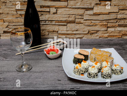 La cuisine japonaise. Dans le café sur la table est une bouteille de vin. Sur la plaque est un ensemble de différents sushi et fruits de mer. Banque D'Images
