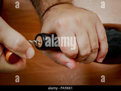 Close up. Les mains des hommes tirer le bouchon d'une bouteille de vin avec un tire-bouchon. Banque D'Images