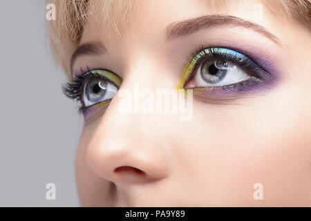 Closeup macro image des droits de l'homme avec des yeux ombres violet, bleu et jaune et un miroir Banque D'Images