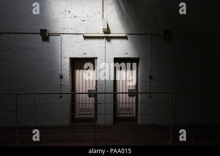 Un rayon de soleil s'allume deux portes des cellules sur un atterrissage à Freemantle prison, de l'Australie. Banque D'Images