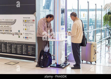 BANGKOK, THAÏLANDE - 21 juillet 2018 - les touristes masculins charger leur téléphone au poste de chargement libre à l'Aéroport International Suvarnaphumi, Bangkok, Thaïlande Banque D'Images