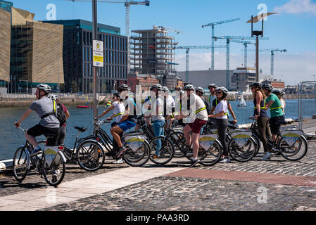 Un groupe de touristes sur les bicyclettes est à la recherche sur la Liffey à Dublin, Irlande. Banque D'Images