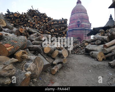 Corps en bois de manguier utilisé dans les rituels de gravure est empilé près d'un temple spire à Manakarnika Ghat, Varanasi, Inde. Banque D'Images