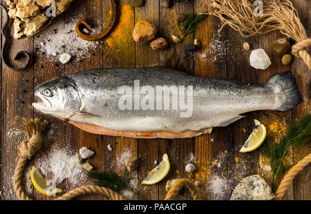 Un saumon de poisson frais se trouve sur les cartes grises. Autour de la mer de cailloux, de tranches de citron et les assaisonnements Banque D'Images