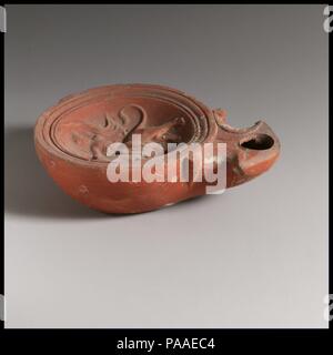 Lampe en terre cuite. Culture : Roman. Dimensions : hors tout : 1 1/8 x 3 à 11/16. (2,9 x 9,4cm). Date : ca. La C.-B. 20-A.D. 25. Type Loeschcke 1A. Faites-moule. Le contre-batteur, profonde et la discus : Europa bull, faisant face à droite ; Europa avec bras droit tendus tenant le bull entre les cornes et le bras gauche relevé tenant des volutes derrière elle ; un seul trou de remplissage en bas près de la buse, et des lignes et des grooves autour du bord. Volutes angulaires d'accompagnement, de buse avec de grands trous de mèche ; petite rainure verticale à la base du bec. Large, base surélevée de l'anneau, et base plate. Intacte, mais une petite puce sur le chant à l'arrière de discus Banque D'Images