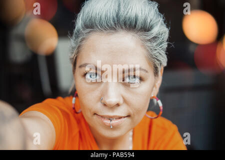 Belle fille blonde pensive en tee-shirt orange de décisions au café selfies Banque D'Images