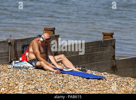 Un homme jouit du beau temps sur la plage de Whitstable, Kent, comme le temps chaud se poursuit. Banque D'Images