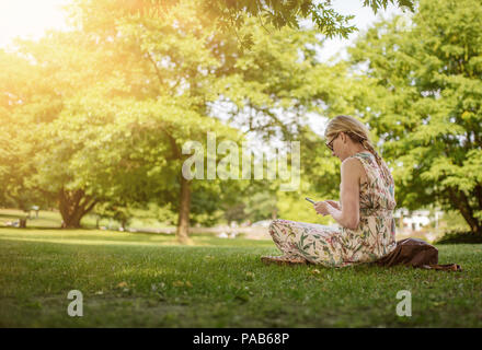 Woman using smartphone en parc public Banque D'Images