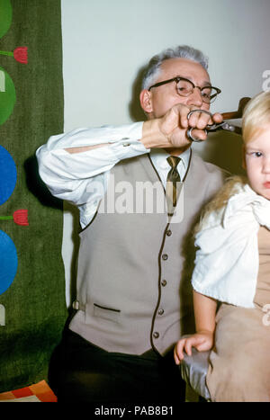 Un grand-père (profession de barbier) Donner une coupe de cheveux à un jeune garçon aux États-Unis dans le années 1960 Banque D'Images